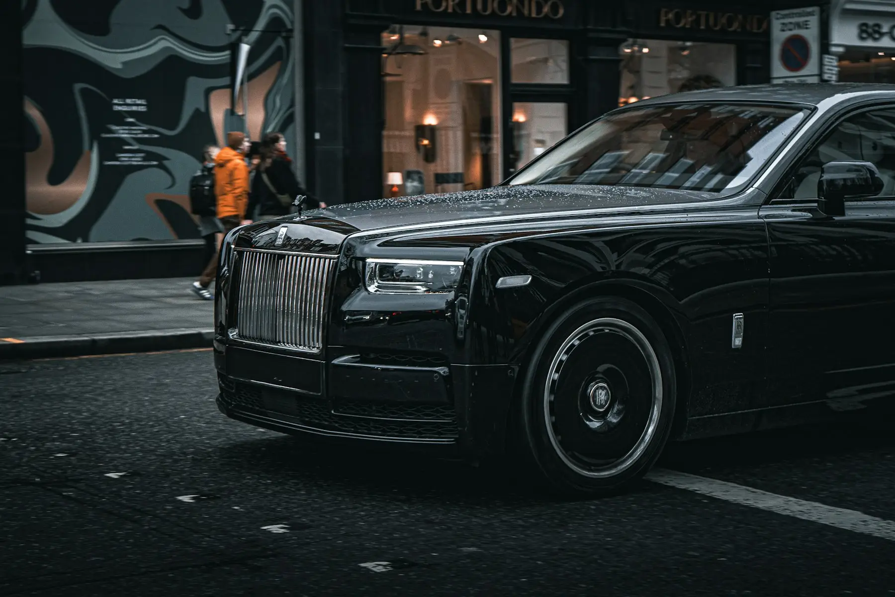 A black Rolls-Royce waiting at the kerb at night