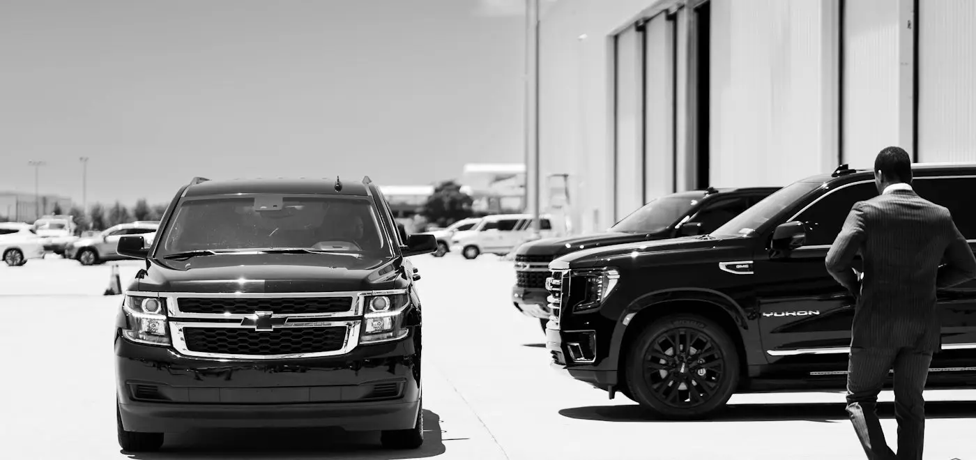 Executive walking past a line of black SUVs